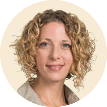 woman with curly hair smiling, professional headshot on neutral background