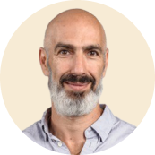 bearded man smiling in light shirt, neutral background, professional portrait with round frame, friendly expression