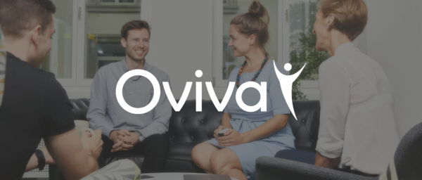 Oviva logo with a group of smiling individuals engaged in conversation on a stylish couch in a modern office setting., Oviva, teamwork