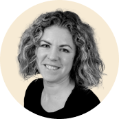 portrait of a smiling woman with curly hair against a light background, professional headshot with engaging expression