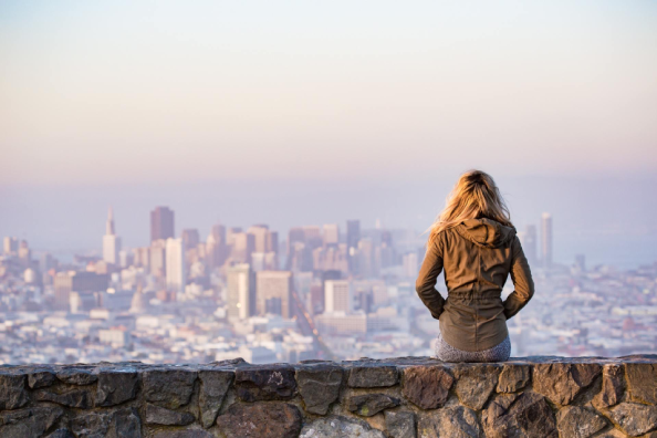 city skyline, person overlooking San Francisco from a stone wall at sunset